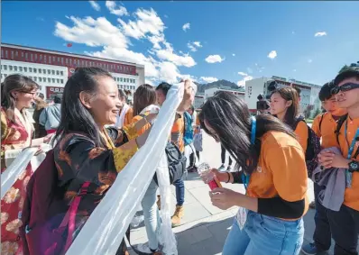  ?? HE PENGLEI / CHINA NEWS SERVICE ?? Students from Tibet University give — pieces of silk used as a greeting gift among Tibetans — to a group of teenagers from Hong Kong, in Lhasa on Thursday. The group of 33 started their six-day visit on Thursday. About 700 teenagers have participat­ed...