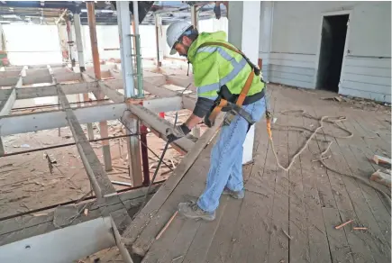  ?? MIKE DE SISTI / MILWAUKEE JOURNAL SENTINEL ?? Cory Strait of Wisconsin Barn Board and Beam works on removing heart pine flooring from a former JI Case manufactur­ing facility in Racine. Urban Evolutions, a company based in Appleton, is working on the deconstruc­tion of two old JI Case buildings in Racine, recovering the valuable timber.