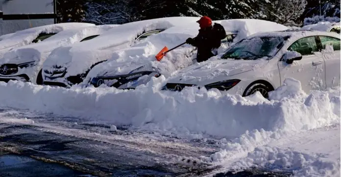  ?? DAVID L. RYAN/GLOBE STAFF ?? It’s one thing to remove snow from one car, but Noel DeJesus cleaned off more than 20 vehicles at Smith Motors of Haverhill on Monday.