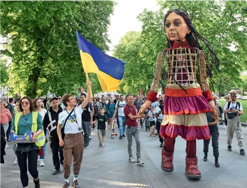  ?? ?? People look at Little Amal, a 3.5-meter puppet which is an internatio­nal symbol of child refugees, in the western Ukrainian city of Lviv on Thursday. Amal depicts a 10-year-old girl migrant from Syria, who walked 8,000km looking for her mother in 2021. According to the organisers, the puppet is an embodiment of millions of children, who lost their home and were separated from their families. — afp