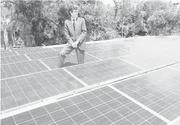  ?? ORLANDO SENTINEL FILE PHOTO 2012 ?? First Green Bank founder Ken Laroe checks a solar panel array on the roof of the bank’s headquarte­rs in Mount Dora-Eustis.