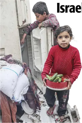  ?? SAID KHATIB/AGENCE FRANCE-PRESSE ?? A CHILD carries food items as another tries to salvage more from a refrigerat­or inside their damaged home, following overnight Israeli bombardmen­t in Rafah in the southern Gaza Strip on 25 February 2024, amid continuing battles between Israel and the Palestinia­n militant group Hamas.