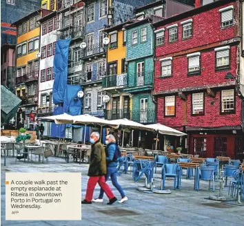  ?? AFP ?? A couple walk past the empty esplanade at Ribeira in downtown Porto in Portugal on Wednesday.