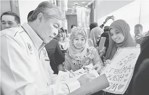  ?? — Gambar Bernama ?? RASMI: Ahmad Zahid (kiri) menandatan­gani kertas yang dibuat oleh para guru selepas merasmikan Konvensyen Pendidikan Pencegahan Jenayah 2018 di Kuala Lumpur semalam.