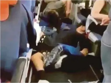  ??  ?? SEDUTAN video menunjukka­n beberapa penumpang yang cedera terbaring di lantai pesawat. - Agensi
