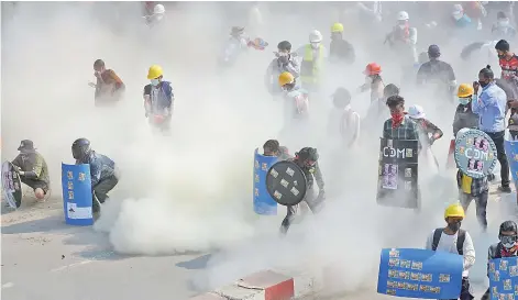  ?? — AFP photos ?? Protesters react after tear gas is fired by police during a demonstrat­ion against the military coup in the northweste­rn town of Kale, Myanmar.