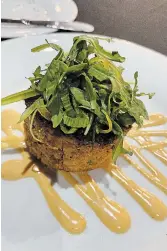  ?? ?? Top, Crab Cake appetizer plated on smoked chorizo aioli and topped with avocado/ cucumber salsa and fine herbs.