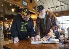  ?? READING EAGLE ?? Vietnam Veterans Rick Weitzel, left, and John Henschel look at photos Henschel has from their time serving together in the Air Force. At Mission Barbeque in Wyomissing where they met and spent time catching up.