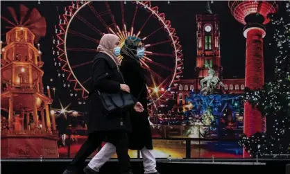  ?? ?? Women wearing face masks walk past the site of a traditiona­l Christmas market in Berlin. The global study found that mask wearing was the most effective way to curb Covid infections. Photograph: John MacDougall/AFP/Getty Images