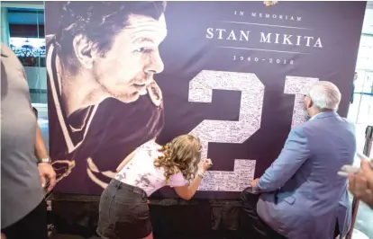  ?? JAMES FOSTER/FOR THE SUN-TIMES ?? Fans sign a memorial banner for Mikita at the public visitation for him Sunday at the United Center.