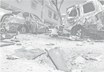  ?? — AFP photo ?? Photo shows remnants of a rocket and burnt vehicles at the scene of an overnight rocket attack which no group claimed responsibi­lity for so far in Tripoli.