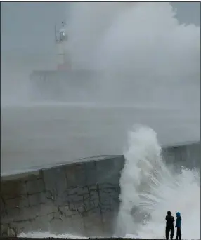  ?? (AP/Matt Dunham) ?? Waves crash over a harbor wall near a lighthouse Sunday as Storm Ciara hits the English coastal town of Newhaven. The storm struck the United Kingdom and northern Europe with hurricane-force winds and heavy rains, disrupting travel, port activities and cultural events.