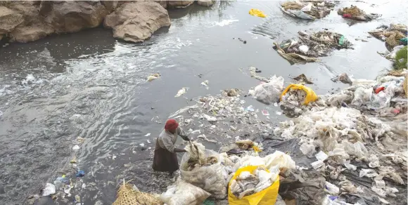  ?? (Siegfried Modola/Reuters) ?? A WOMAN RECYCLES plastic bags from a river close to the slum of Korogocho in Nairobi, the capital of Kenya, in 2015.