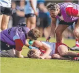  ??  ?? Sydney Swans player Jake Brown is attended by medical staff during the game.