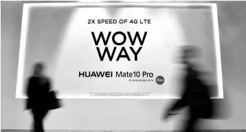  ??  ?? Attendees walk by an advertisem­ent for the Huawei Mate 10 Pro smartphone at the Huawei booth during CES 2018 at the Las Vegas Convention Center on January 10. Chinese tech giant Huawei faces a major setback in efforts to expand in the US smartphone...