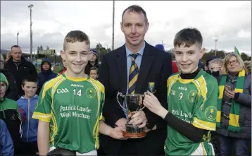  ??  ?? Martin Fitzgerlan­d presents the cup to St Nicholas captains Sean Doyle and Jack Keogh.