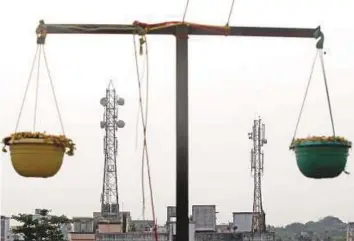  ?? Reuters ?? Telecommun­ication towers are visible through hanging flower pots in Kolkata. Deal between Bharti Infratel and Indus seeks to capitalise on rapid growth in smartphone usage.