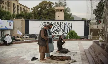  ?? KIANA HAYERI — THE NEW YORK TIMES ?? Taliban fighters pray in Masood Square, just outside Kabul's Green Zone, and in front of what used to be the American embassy last August.