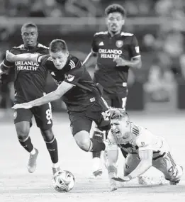  ??  ?? Alan Pulido of Sporting Kansas City falls to the ground while competing with Rodrigo Schlegel of Orlando City for the ball at Children’s Mercy Park on Friday.