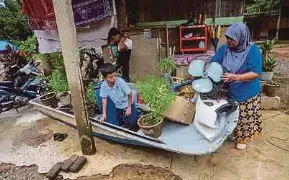  ?? ?? Nur Hayati Ismail bersama anaknya membuat persiapan memindahka­n peralatan rumah ke dalam bot sebagai persediaan hadapi banjir di Kampung Pengkalan Ajal.