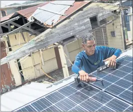  ?? DENNIS M. RIVERA PICHARDO — THE ASSOCIATED PRESS ?? Julio Rosario instals a solar energy system at a home in Adjuntas, Puerto Rico. The nonprofit environmen­tal group Casa Pueblo has installed solar systems at two hardware stores, one barbershop and several corner stores that activists hopewill serve as...