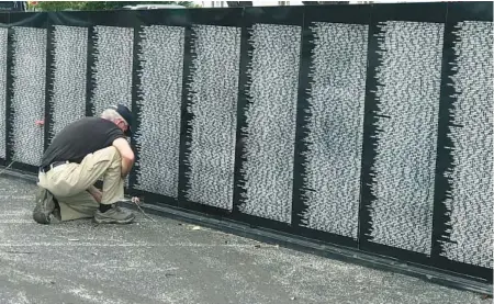  ?? CHRIS PERKINS/SOUTH FLORIDA SUN SENTINEL ?? Herb Sennett, a West Palm Beach resident and U.S. Army veteran who served in Vietnam, bows in front of the Vietnam Traveling Memorial Wall that bears the name of a buddy and fellow soldier. The exhibit is on display at the Hilton Palm Beach Airport through Sunday.