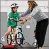  ?? ST. LOUIS POST-DISPATCH ?? Physical Education teacher Natalie Luna helps first grader Camille Holborow who rides a ramp for the first time on her balance bike.