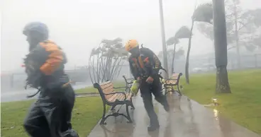  ?? /Reuters ?? Storm troopers: Members of the civil defence in Fajardo, Puerto Rico, run as Hurricane Irma howls past after thrashing several smaller Caribbean islands, killing at least eight people.