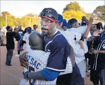  ?? Photograph­s by Allen J. Schaben Los Angeles Times ?? PLAYERS embrace after the Twins, representi­ng South L.A.’s Rollin’ 30s neighborho­od, defeated the Brewers, representi­ng the Rollin’ 40s, in the Crips softball championsh­ip game at El Nido Park in Torrance.