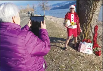  ?? RON SEYMOUR/The Daily Courier ?? Peggy Worobetz takes pictures of her husband Ted, dressed as Santa Claus, on Wednesday afternoon along the shore of Okanagan Lake in Peachland. The couple will use the picture for their Christmas cards next year.