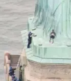  ??  ?? This image from video shows a person leaning against the robes of the Statue of Libery as police officer approach on Wednesday in New York.