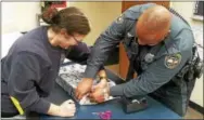  ?? SUBMITTED PHOTO ?? Coatesvill­e police receptioni­st Robin Smith and Officer Sylvester Earle wrap a gift to deliver to a family in need during Christmas.