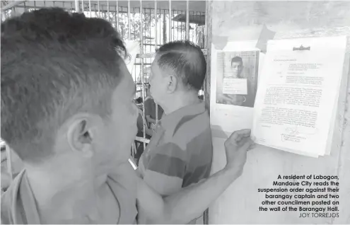  ?? JOY TORREJOS ?? A resident of Labogon, Mandaue City reads the suspension order against their
barangay captain and two other councilmen posted on the wall of the Barangay Hall.