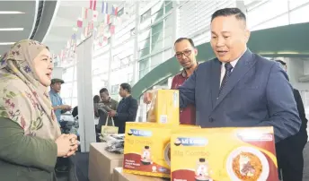  ?? — Photo by Chimon Upon ?? Willie (right) checks out an entreprene­ur’s products at her booth set up in BCCK in conjunctio­n with the Maskop Madani programme. Looking on is IKMa deputy director general (Human Capital Developmen­t) Mohd Zaib Yunus.