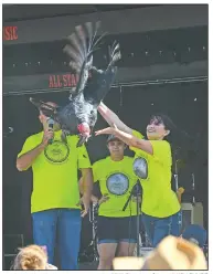  ?? NWA Democrat-Gazette/ANDY SHUPE ?? Festival officials release a wild turkey from the stage Saturday during the annual Turkey Trot in Yellville.