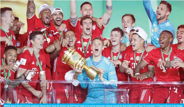  ?? —AFP ?? BERLIN: Bayern Munich’s German goalkeeper Manuel Neuer raises the German Cup (DFB Pokal) trophy as he and his teammates celebrate winning the final football match Bayer 04 Leverkusen v FC Bayern Munich at the Olympic Stadium in Berlin.