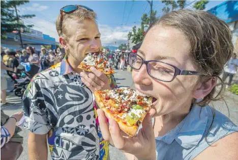  ?? ARLEN REDEKOP ?? Stefan Gronsdahl and Mehan Seiling eat pizza during Italian Day festivitie­s on Commercial Drive on Sunday.