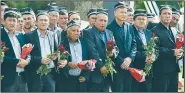  ?? AP ?? People hold flowers Saturday as they gather along the road to watch the funeral procession of President Islam Karimov in Samarkand, Uzbekistan.