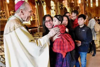  ?? ?? Bishop Emeritus Howard Hubbard, left, greets 8-month-old Samantha Buban of Albany and her mother, Wowwie Buban, after Christmas Mass on Dec. 25, 2015, at the Cathedral of the Immaculate Conception in Albany.