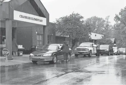  ??  ?? Cars wait for deliveries of prepackage­d breakfast and lunch outside Chandler Elementary in southern Indiana. As program costs soar across the nation, revenue has shrunk. PHOTOS BY SHENAE ROWE/WARRICK COUNTY SCHOOL CORP.