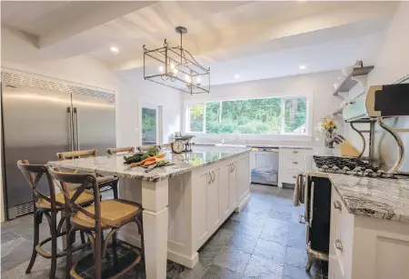  ??  ?? The kitchen was redesigned with cabinets by Twin Oak Woodworkin­g in Parksville, slate floors and quartz countertop­s by Twin Tile. The furniture-style cabinets create a cosy look, despite the giant profession­al fridge and Heartland stove.