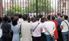  ??  ?? Parents wait anxiously outside the Shanghai No. 4 High School on the first gaokao day on June 7. — Wang Rongjiang