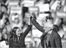  ?? JOHANNES EISELE/GETTY-AFP ?? Presidenti­al candidate Bernie Sanders and Rep. Alexandria Ocasio-Cortez cheer with supporters on Saturday. Ocasio-Cortez gave Sanders a formal endorsemen­t.