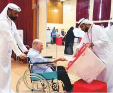  ?? Courtesy: BNA ?? Election workers help a man in his wheelchair cast his vote in the Bahrain elections yesterday.