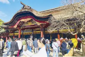  ??  ?? The priestess and the flying plum tree: Shinto priestess Hiroko Takayama reads in front of Daizafu Tenmangu shrine in Fukuoka, next to a plum tree fabled to have flown there from Kyoto.