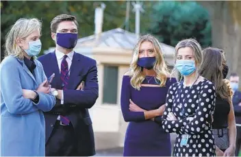  ?? ALEX BRANDON AP ?? White House press secretary Kayleigh McEnany (third from left) waits with other staffers as President Donald Trump prepares to leave the White House to go to Walter Reed National Military Medical Center Friday.