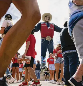  ?? Lola Gomez/Dallas Morning News ?? Big Tex towers over fairgoers at the 2021 State Fair of Texas in Dallas. Big Tex is 55 feet tall and wears a size 96 Lucchese boot. His jeans weigh 100 pounds.