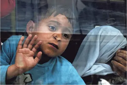  ?? SIMELA PANTZARTZI, EUROPEAN PRESSPHOTO AGENCY ?? A boy looks out of a bus window as refugees from Syria and Iraq board a bus transferri­ng them to a new facility in Attica from the port of Piraeus, Greece, in April.