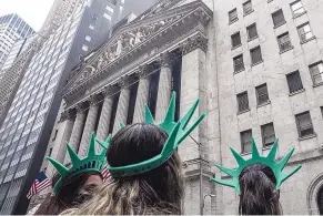  ?? BEBETO MATTHEWS/ASSOCIATED PRESS ?? Visitors to New York City wear Lady Liberty souvenir headgear while standing outside the New York Stock Exchange on Wall Street in May. U.S. stocks ticked higher on Monday.