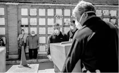  ?? AP ?? The daughter and husband (left) no names available, of an elderly victim of the COVID-19 stand as undertaker­s place the coffin in the grave at the Almudena cemetery in Madrid, Spain, Saturday, March 28. In Spain, where stay-at-home restrictio­ns have been in place for nearly two weeks, the official number of deaths is increasing daily. The new coronaviru­s causes mild or moderate symptoms for most people, but for some, especially older adults and people with existing health problems, it can cause more severe illness or death.